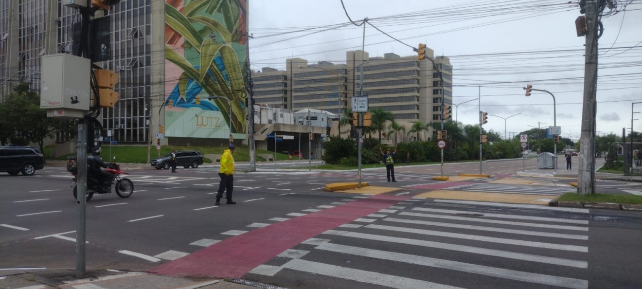 Dois guardas de trânsito orientam tráfego no cruzamento da avenida Borges de Medeiros e Aureliano de Figueiredo Pinto. Ao fundo, os prédios do Daer e o Foro Central 1, que está sem luz.