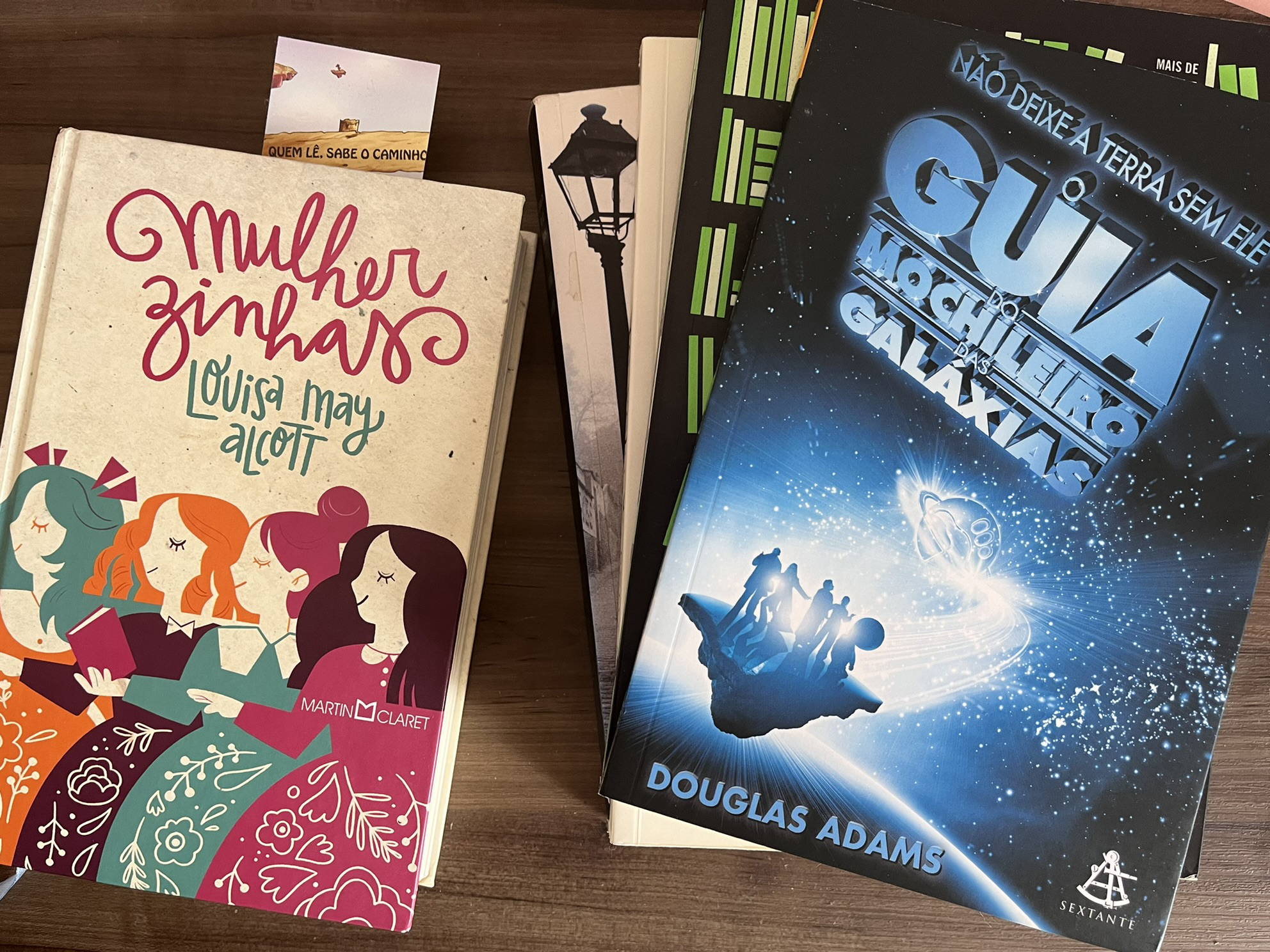 Cinco livros sobre uma mesa de madeira