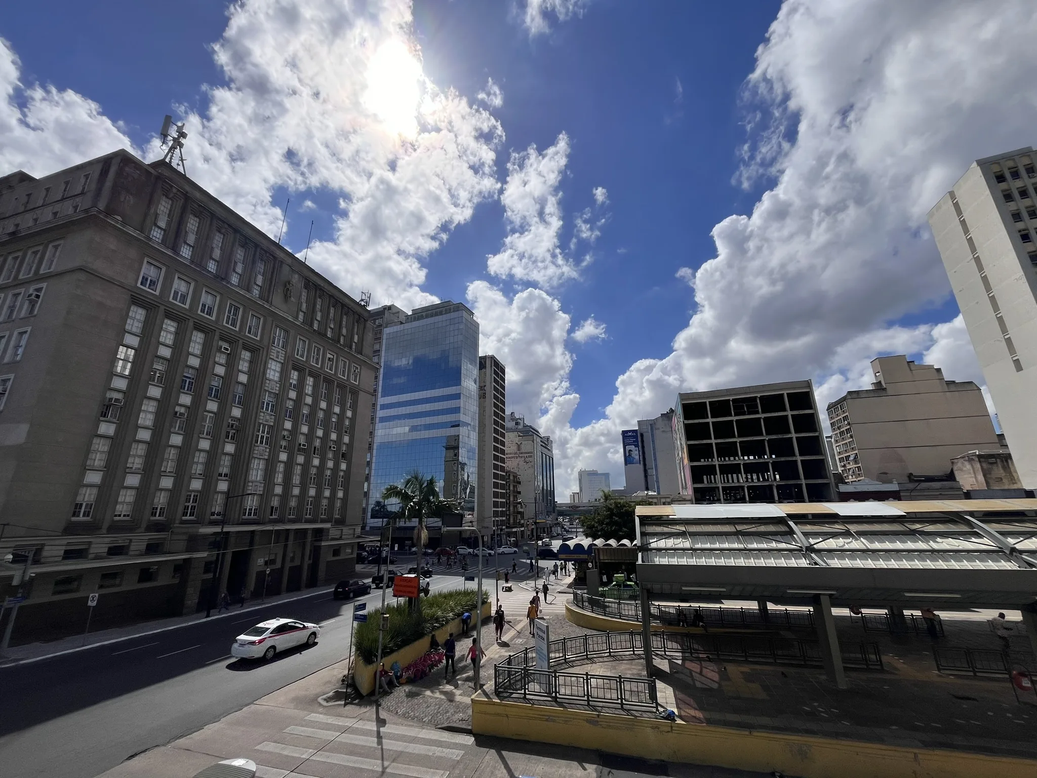 Vista do segundo andar do Mercado Público de Porto Alegre mostra a Praça Pereira Parobé em dia de sol entre nuvens.