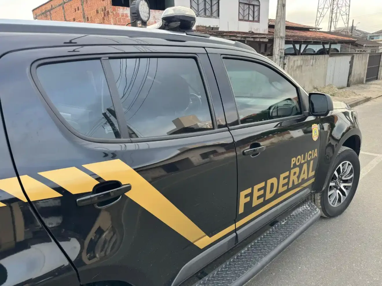 Imagem de um carro da Polícia Federal do Brasil, com detalhes em preto e amarelo, estacionado em uma rua.