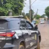 Veículo da Polícia Civil estacionado em uma rua, com um policial em uniforme tático, observando o ambiente ao redor.