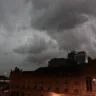 Céu nublado com nuvens escuras sobre edifícios e luzes do Centro de Porto Alegre durante a noite.