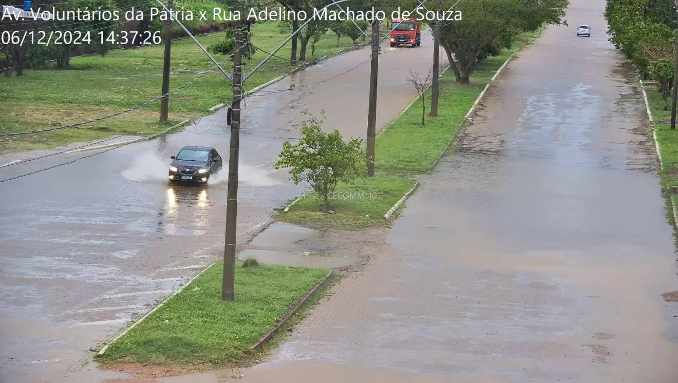 Imagem mostrando a interseção da Avenida Voluntários da Pátria com a Rua Adelino Machado de Souza durante forte chuva, com água acumulada nas ruas.