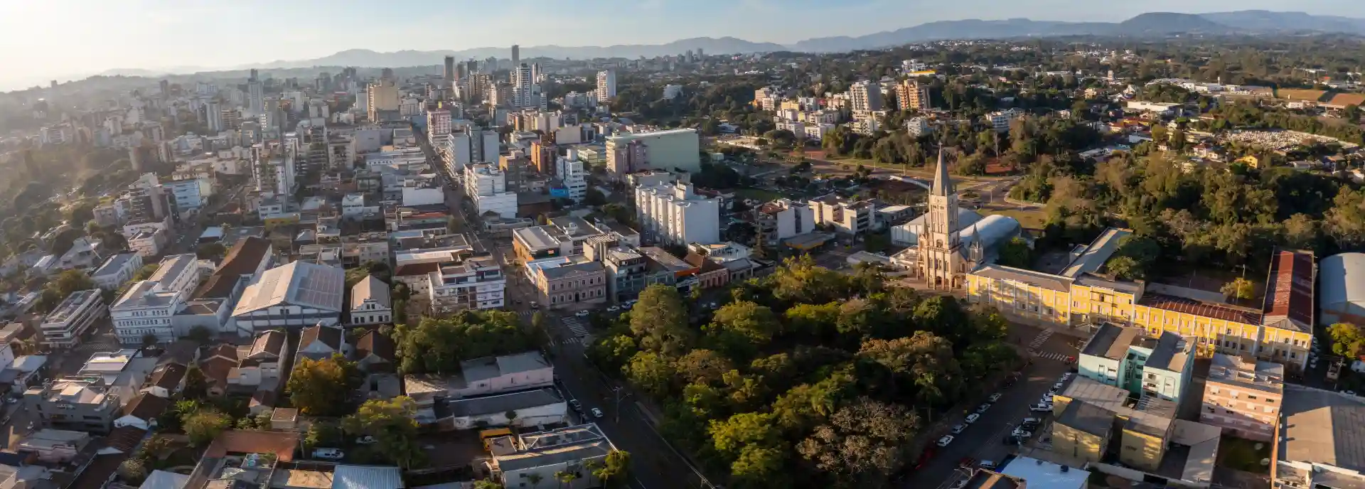 Imagem aérea da cidade de Lajeado, destacando a urbanização e as áreas verdes em um panorama impressionante.