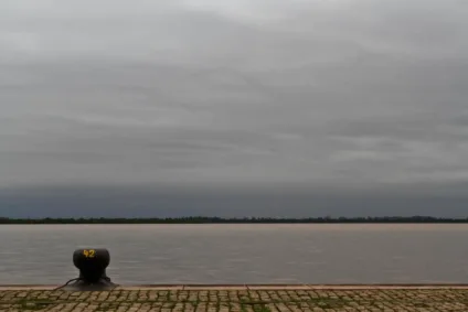 Vista do Cais do Porto em Porto Alegre, destacando o imponente céu cinza e o cais de pedra ao lado da água serena.