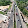 Vista aérea das obras na BR-386, em Estrela, com várias faixas de tráfego e cones de sinalização, rodeada por vegetação.