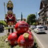 Decoração natalina com um boneco de madeira e enfeites vermelhos de Natal, mostrando uma calorosa recepção com a mensagem 'Bem Vindos'.