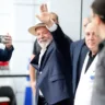 Presidente Lula deixa hospital em São Paulo, sorrindo e acenando para a multidão, com forte presença da mídia.