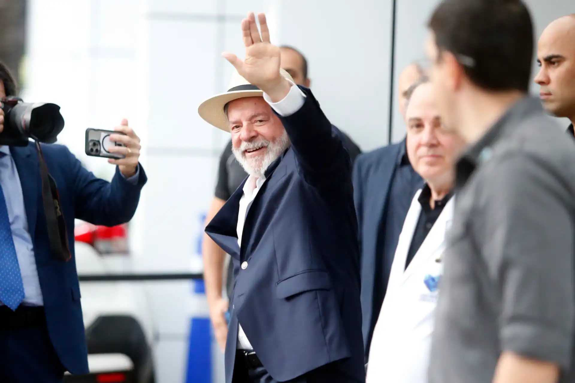 Presidente Lula deixa hospital em São Paulo, sorrindo e acenando para a multidão, com forte presença da mídia.