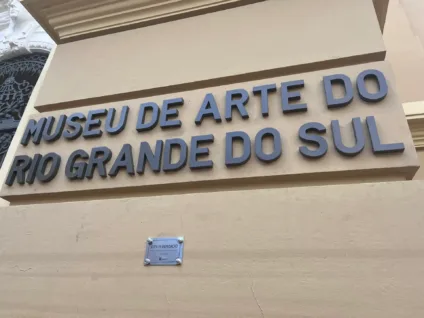 Placa de entrada do Museu de Arte do Rio Grande do Sul, destacando seu nome e placa com marca da inundação da enchente de 2024.