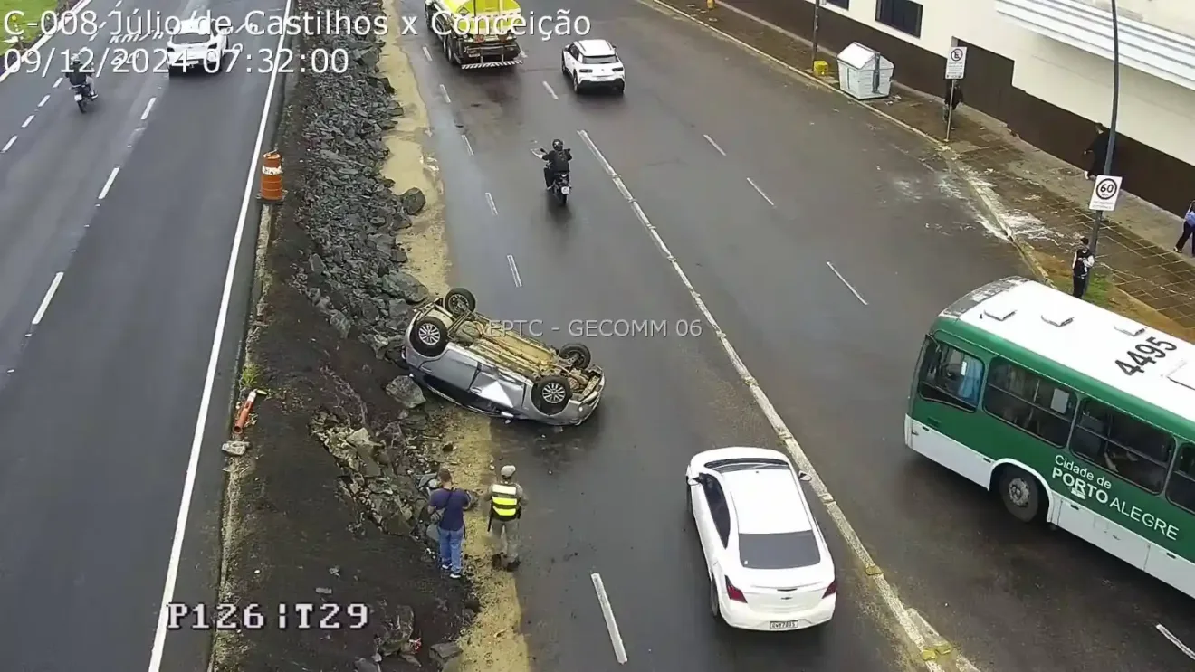 Imagem de um acidente de carro na descida da avenida Castello Branco para o Túnel da Conceição, com um veículo capotado e a presença de motociclistas e carros