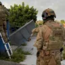 Operação policial com agentes da CORE utilizando escadas para acessar uma área restrita. A imagem retrata a ação da polícia em combate ao crime.