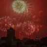 Festa com fogos de artifício iluminando o céu noturno, com explosões coloridas em meio a prédios de Porto Alegre.