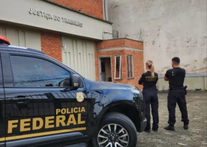 Veículo da Polícia Federal em frente ao prédio da Justiça do Trabalho em Canoas, na região metropolitana. Os agentes estão de costas, em foto posada.