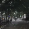 Imagem de uma rua inundada com carros e um ônibus, sob uma luz verde de semáforo, após tempestade em Porto Alegre.