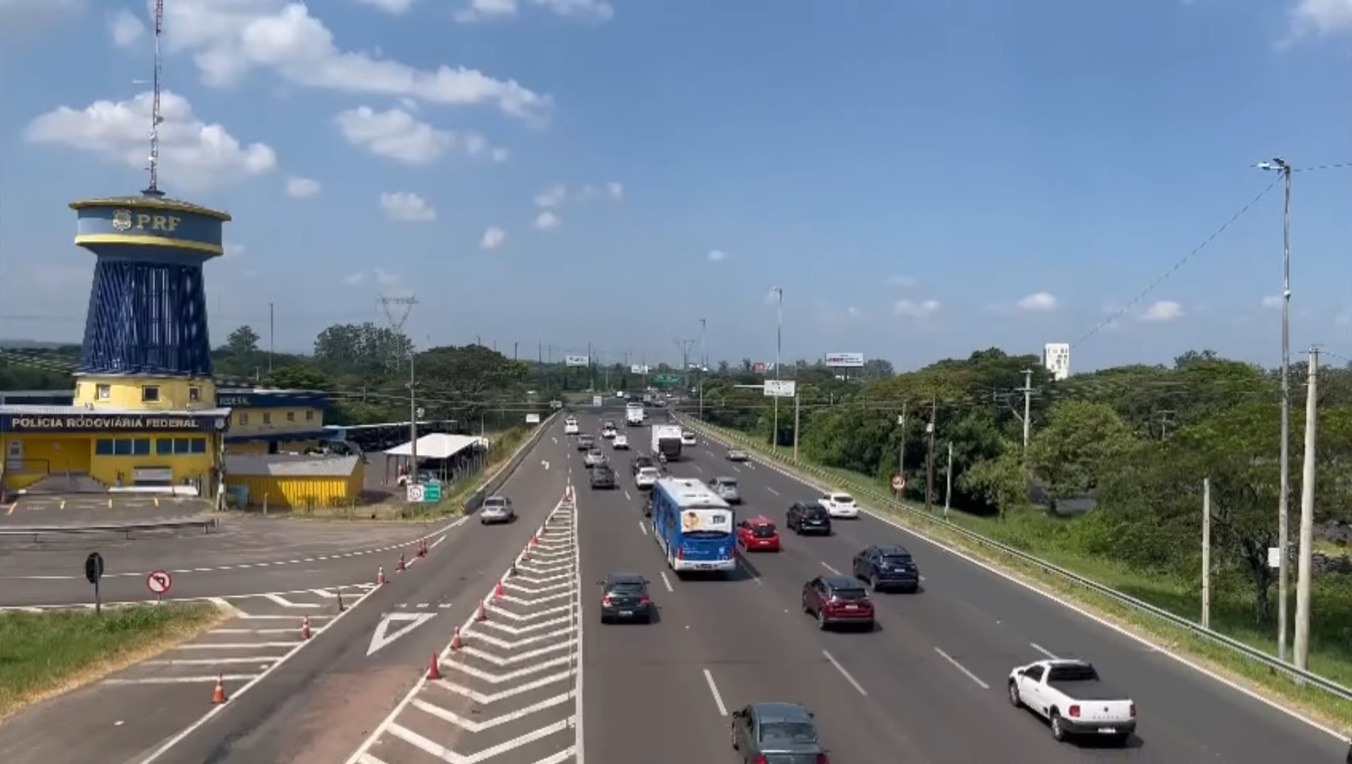 Imagem da Freeway na saída de Porto Alegre, com intenso fluxo de veículos e a presença da Polícia Rodoviária Federal ao lado da rodovia.