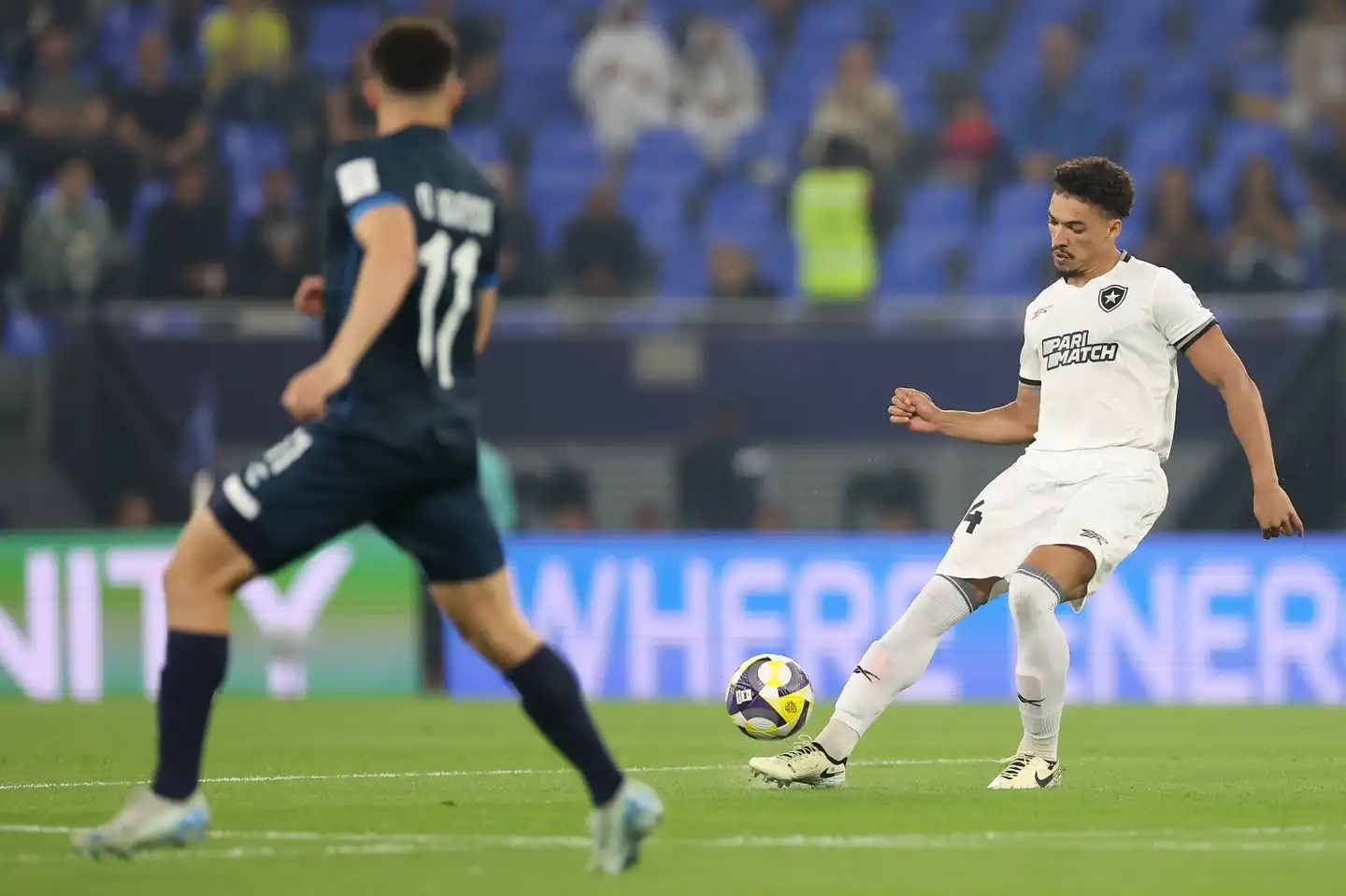 Jogador do Botafogo em ação durante partida, vestindo uniforme branco, em confronto contra o Pachuca com camisa escura.