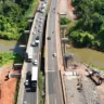 Vista aérea das obras na ponte do Arroio Boa Vista, com tráfego intenso de veículos, cercada por vegetação densa e um rio ao lado.