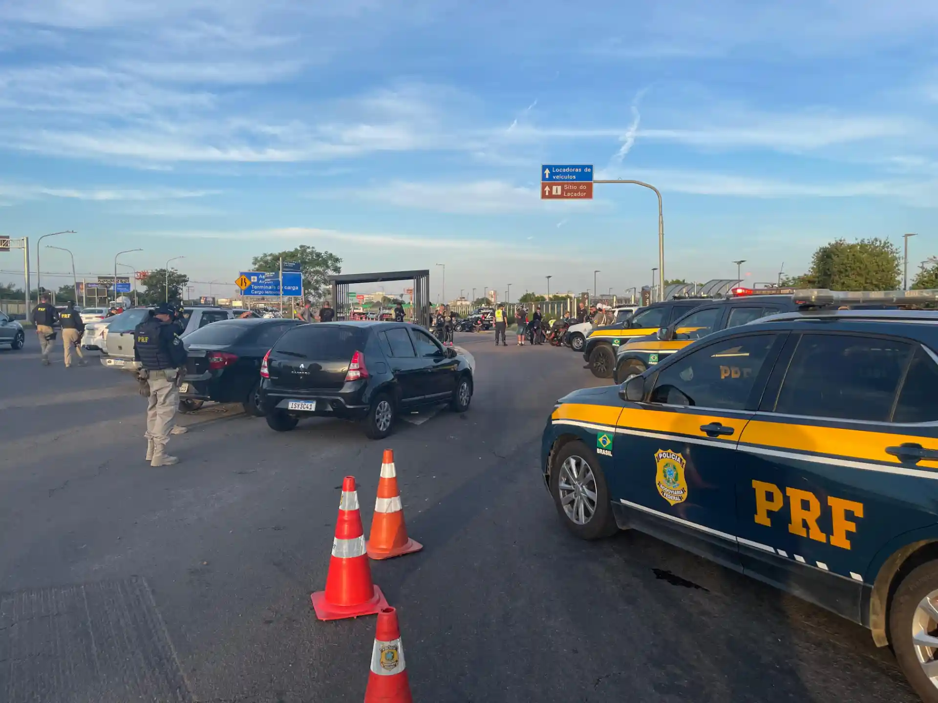 Imagem de uma operação de fiscalização da PRF com carros e cones de sinalização. Agentes da EPTC, do CRBM e Polícia Civil estão presentes na cena.