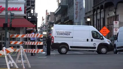 Van do legista do Orleans Parish em frente a um bloqueio de rua, evidenciando a presença da polícia em uma operação.