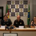 Coletiva da Pol&iacute;cia Civil do Rio Grande do Sul com representantes da institui&ccedil;&atilde;o em uma sala de imprensa, acompanhados da bandeira do Brasil.