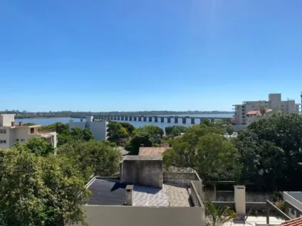 Vista panorâmica do rio Uruguai com a Ponte Internacional e prédios ao fundo em um dia ensolarado.