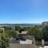 Vista panorâmica do rio Uruguai com a Ponte Internacional e prédios ao fundo em um dia ensolarado.