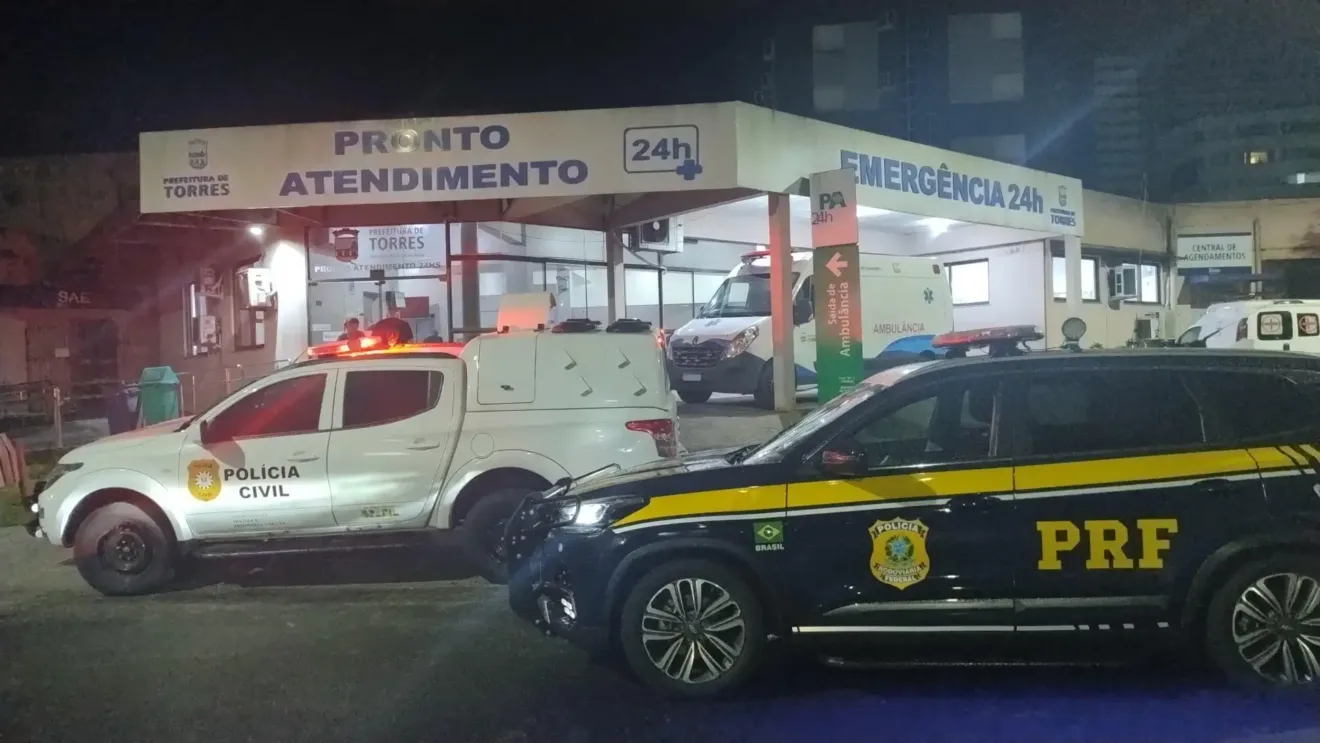 Imagem noturna de um pronto atendimento, a emergência 24 horas em Torres, com presença de viaturas da Polícia Civil e PRF, destacando.