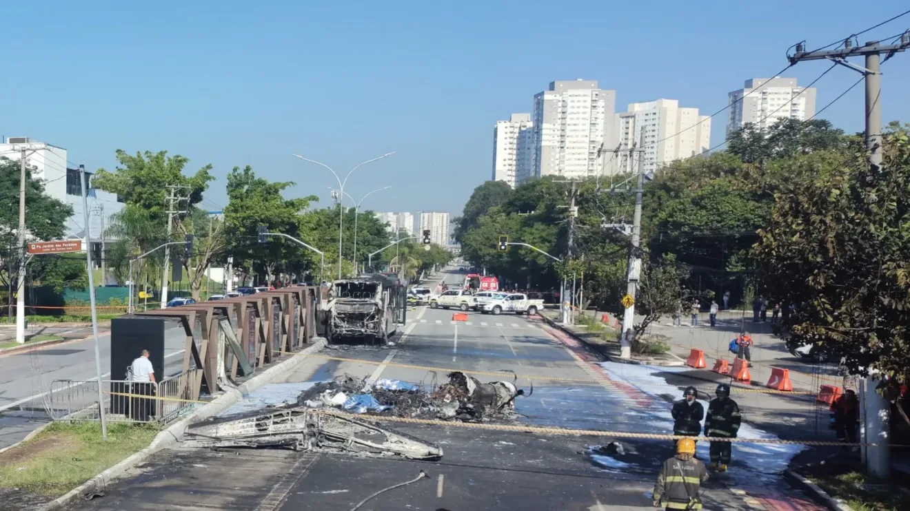 Cenário de um acidente onde um avião tentou pousar de emergência e colidiu com um ônibus. A imagem mostra destroços e a presença de equipes de emergência.