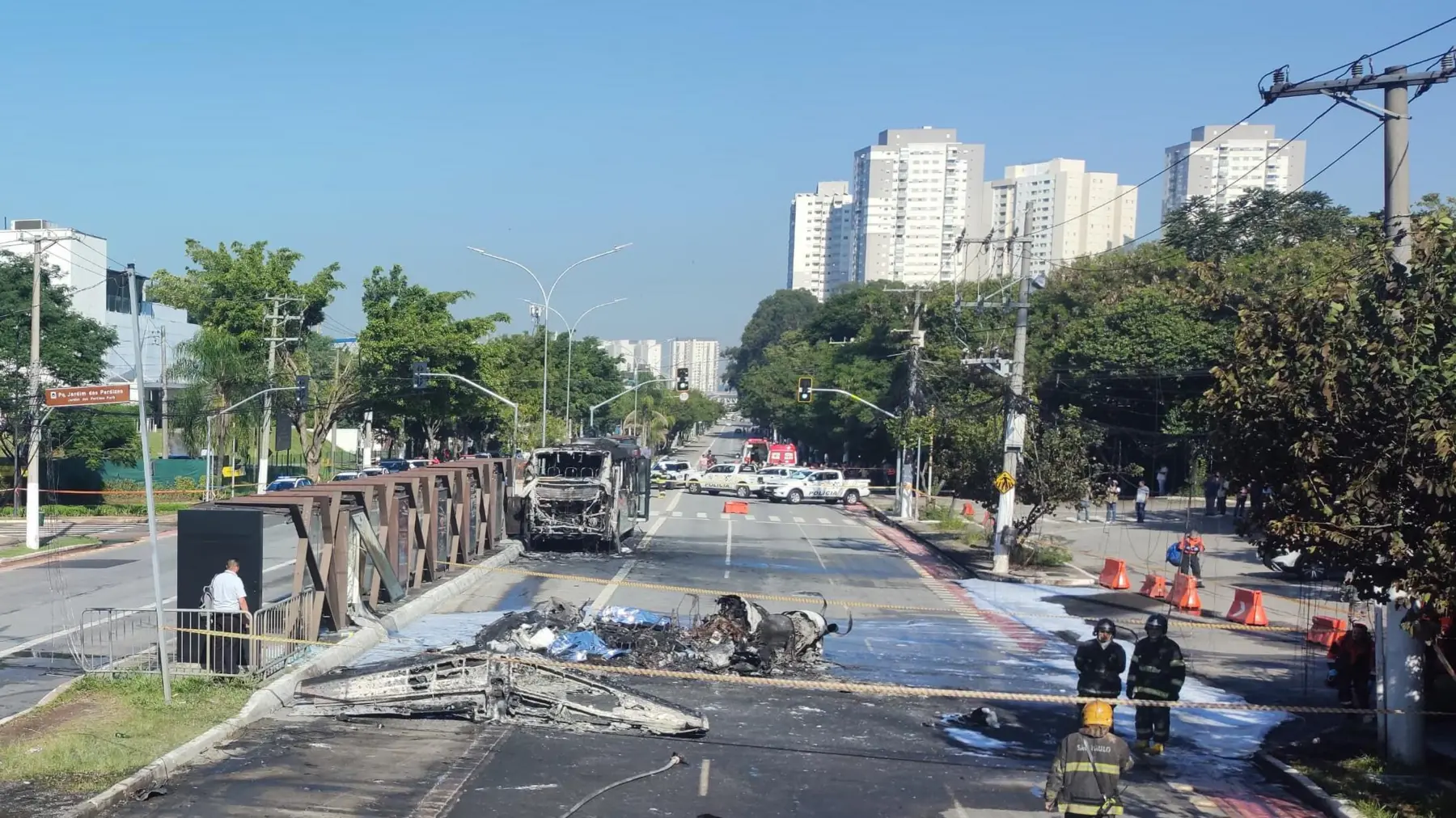 Cenário de um acidente onde um avião tentou pousar de emergência e colidiu com um ônibus. A imagem mostra destroços e a presença de equipes de emergência.