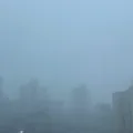 Vista da cidade de Porto Alegre durante uma chuva intensa, com pr&eacute;dios cobertos pela precipita&ccedil;&atilde;o e baixa visibilidade.