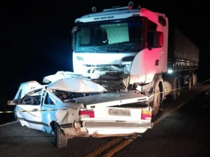 Imagem de um acidente de trânsito noturno envolvendo um caminhão e um carro, mostrando a gravidade dos danos visíveis.