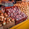 Barracas da Feira Livre no Largo Zumbi dos Palmares em Porto Alegre, exibindo uma variedade de legumes e cebolas frescas