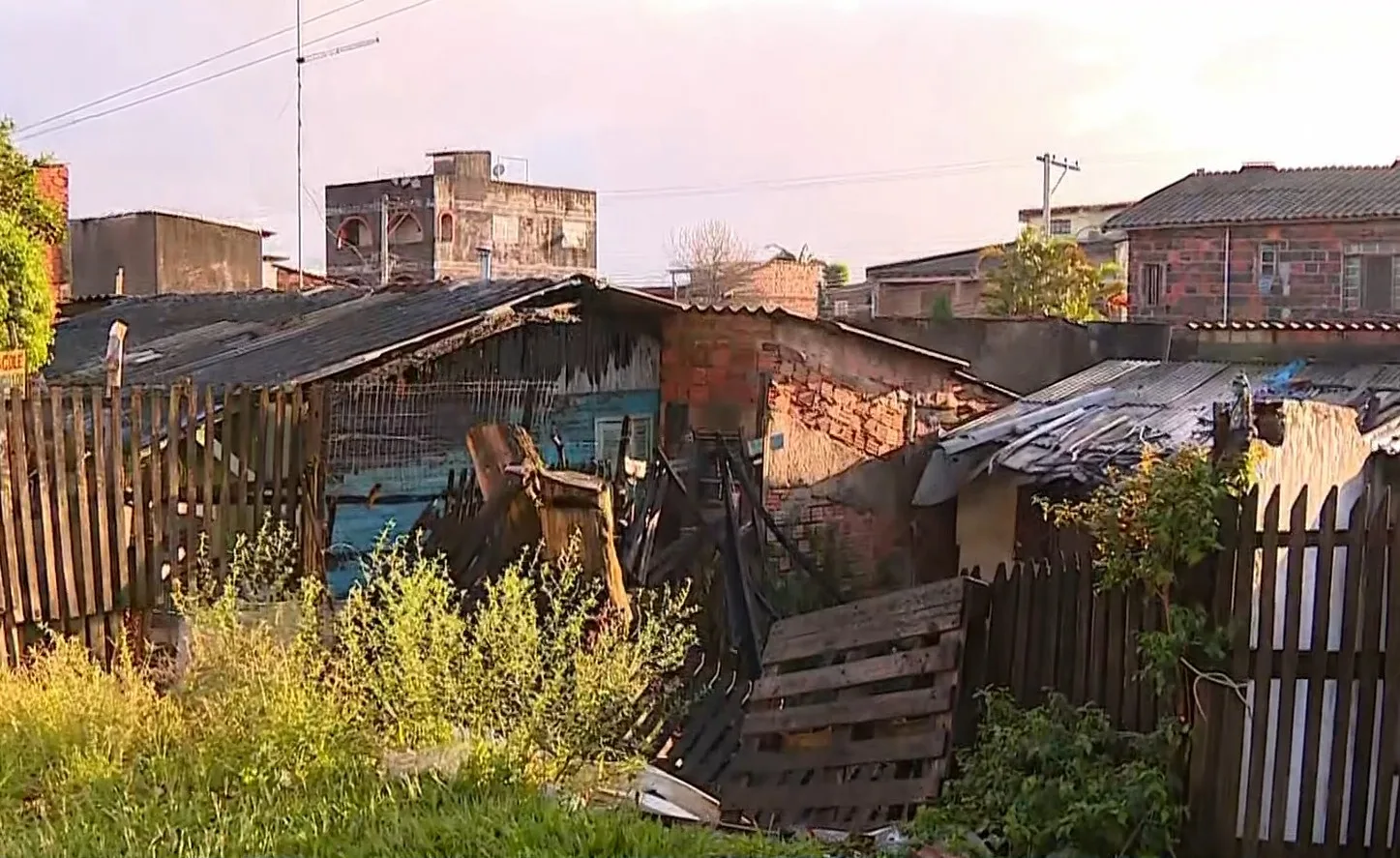 Imagem do bairro Sarandi mostrando áreas danificadas por incêndio, com estruturas de madeira queimadas e vegetação ao redor.