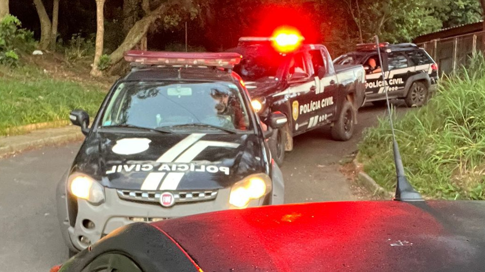 Imagem de viaturas da Polícia Civil em ação. Carros estão com luzes vermelhas em um cenário urbano