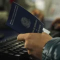 Pessoa segurando a carteira de trabalho brasileira e utilizando um teclado, representando a busca por emprego e formaliza&ccedil;&atilde;o de trabalho.