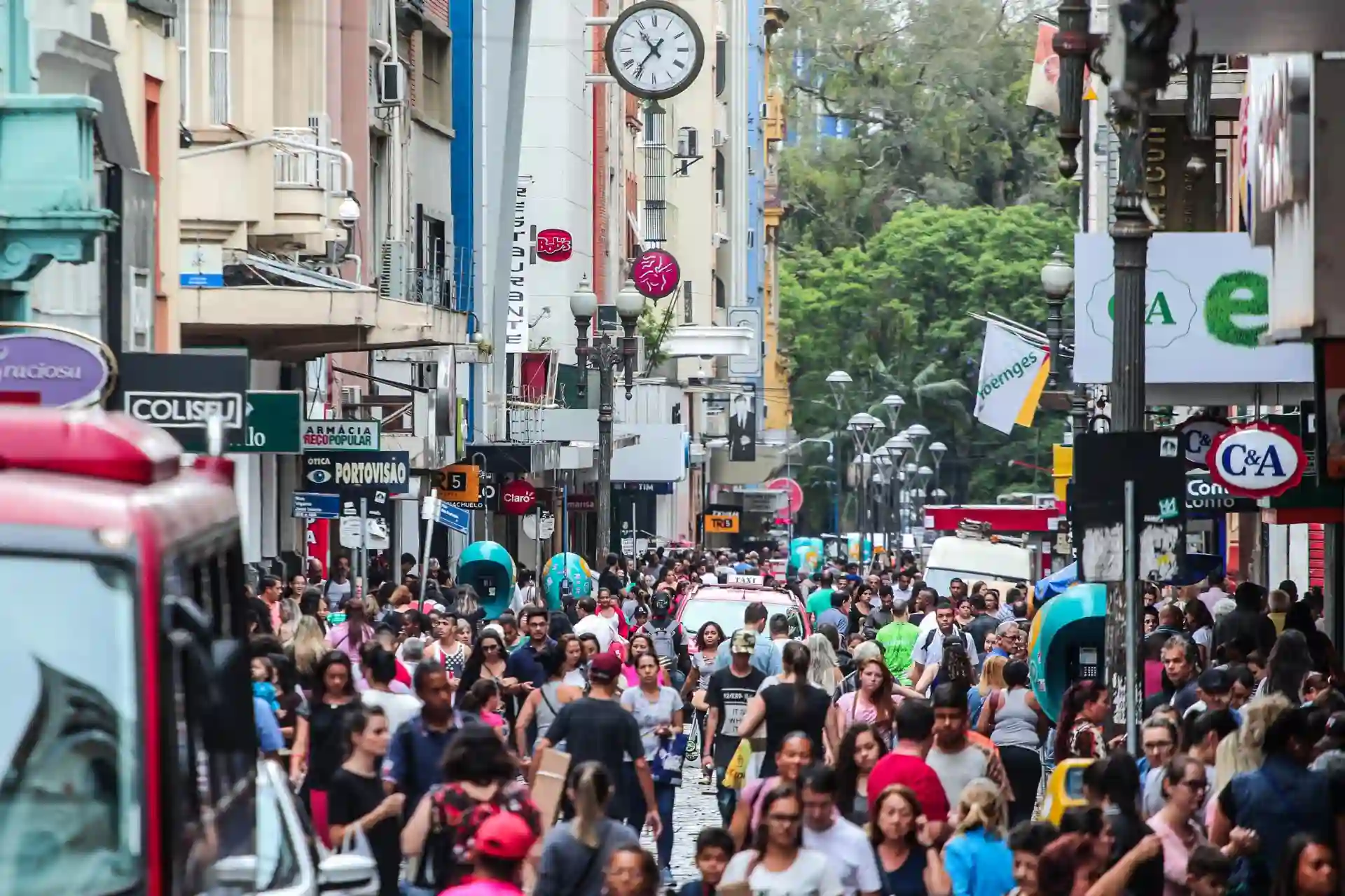 Rua dos Andradas, no Centro Histórico de Porto Alegre, repleta de pessoas e pontos de comércio.