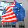 Bandeiras dos Estados Unidos e da União Europeia tremulando juntas.