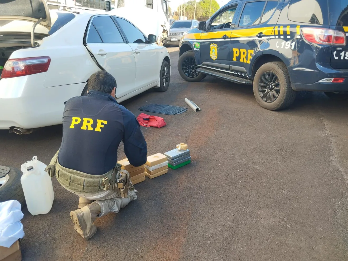 Agentes da PRF recolhem a droga do interior de veículo branco