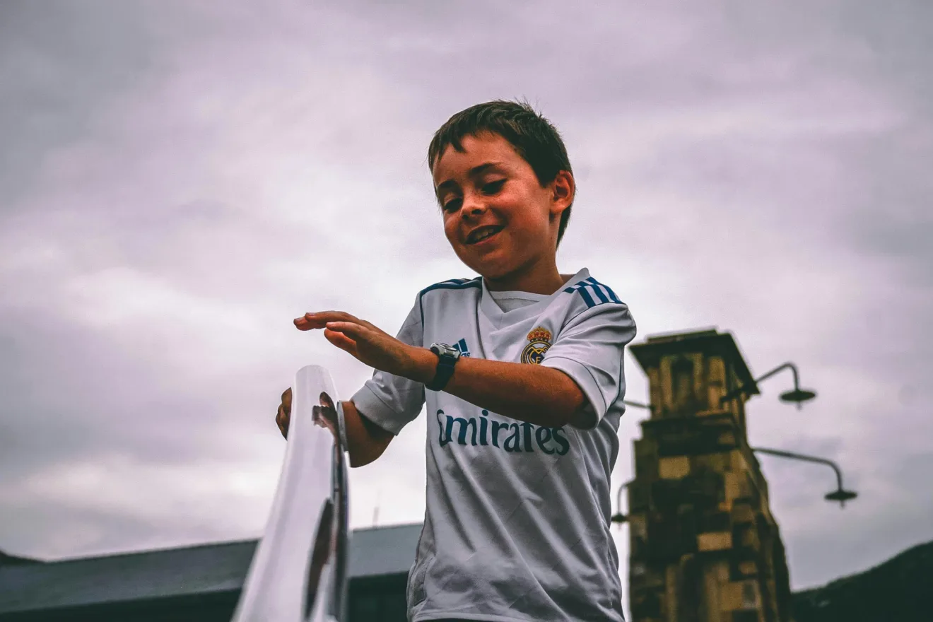 Foto de Darcy Lawrey: https://www.pexels.com/pt-br/foto/garoto-com-camisa-branca-e-azul-fly-emirates-jersey-segurando-na-escada-barra-de-apoio-sob-o-ceu-cinza-913501/