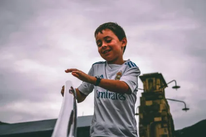 Foto de Darcy Lawrey: https://www.pexels.com/pt-br/foto/garoto-com-camisa-branca-e-azul-fly-emirates-jersey-segurando-na-escada-barra-de-apoio-sob-o-ceu-cinza-913501/