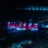 Foto panorâmica do palco do Show da Lady Gaga em Copacabana. É noite e há luzes coloridas e milhares de pessoas