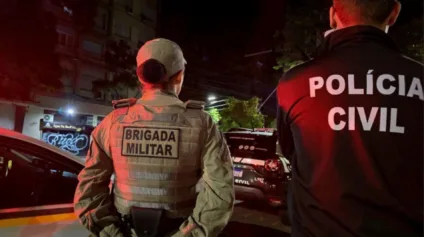 Imagem de policiais militares e civis em operação noturna na rua, com viaturas e iluminação urbana. Imagem de policiais militares e civis em operação noturna na rua, com viaturas e iluminação urbana.