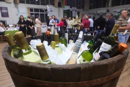 Garrafas de vinho em um barril com gelo, com pessoas ao fundo