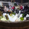 Garrafas de vinho em um barril com gelo, com pessoas ao fundo