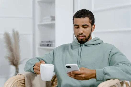 <a href="https://www.pexels.com/photo/a-man-in-gray-hoodie-holding-a-cup-of-coffee-while-using-a-smartphone-8217363/" target="_blank" rel="noreferrer noopener"><strong>Photo by MART  PRODUCTION, Pexels</strong></a>
