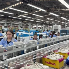 Funcionários de uma fábrica de calçados operando na linha de produção.