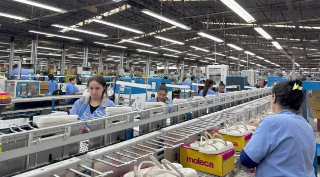 Funcionários de uma fábrica de calçados operando na linha de produção.
