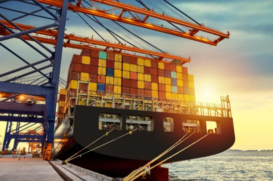 Huge panamax size container vessel discharging and loading container cargo at port terminal. Quay crane pick up container from truck onto ship.