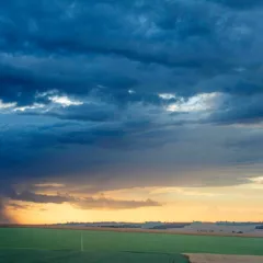 Imagem de lavoura com céu carregado e sol no fundo. Crédito: Fernando Dias/Seapi

